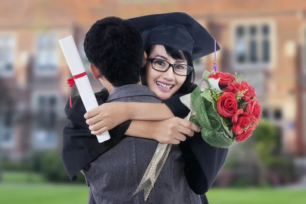 Estudante com mortarboard abraça seu namorado — Fotografia de Stock