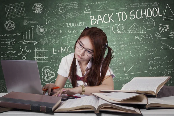 Κορίτσι, μελετώντας με τον φορητό υπολογιστή στο γραφείο στην τάξη — Φωτογραφία Αρχείου