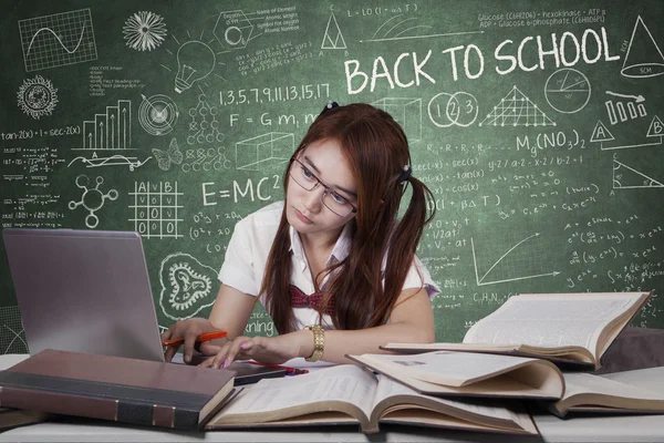 Fille étudiant avec ordinateur portable sur le bureau en classe — Photo