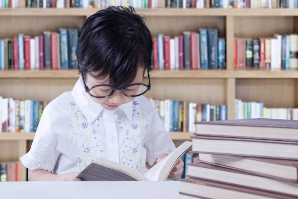 Estudante adorável lê livros na biblioteca — Fotografia de Stock