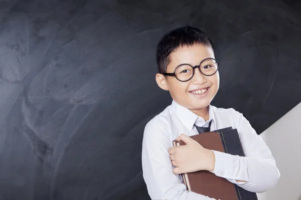 Glad pojke håller bok i klassrummet — Stockfoto