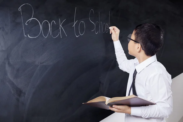 Kind met boek schrijven tekst terug naar School — Stockfoto