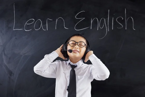 Lindo chico aprende inglés con auriculares — Foto de Stock