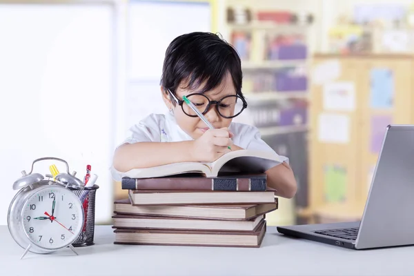 Meisje leert met boeken en laptop in de klas — Stockfoto