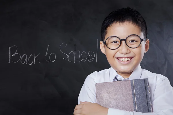 Joyful skolpojke innehåller boken i klass — Stockfoto