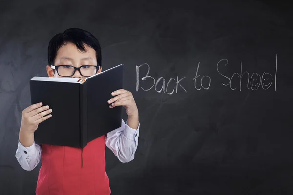 Criança com texto Back to School lê livro — Fotografia de Stock