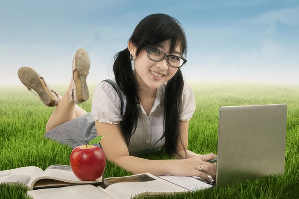 Asian schoolgirl learns on meadow — Stock Photo, Image