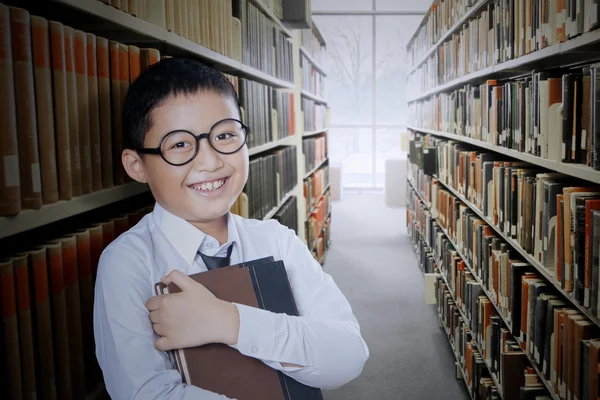 Boy tient un livre dans l'allée de la bibliothèque — Photo