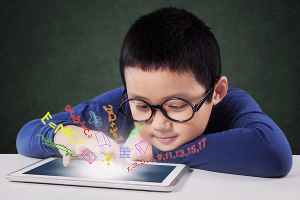 Menino aprende com tablet na mesa na sala de aula — Fotografia de Stock
