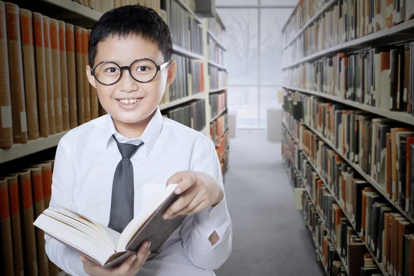 Bambino legge libro nella navata della biblioteca — Foto Stock