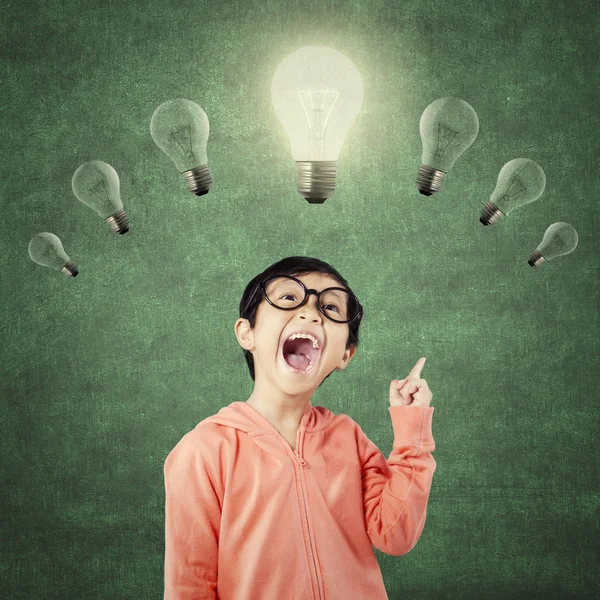 Genius child pointing at bright light bulb — Stock Photo, Image