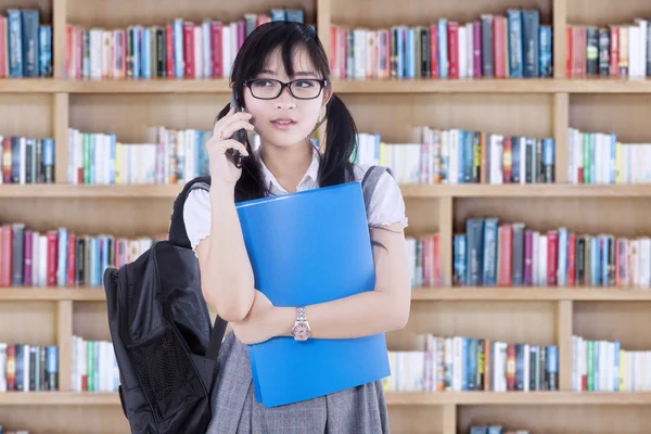 Menina falando ao telefone na biblioteca — Fotografia de Stock