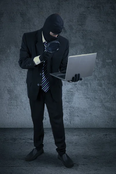 Thief holds laptop with magnifier — Stock Photo, Image