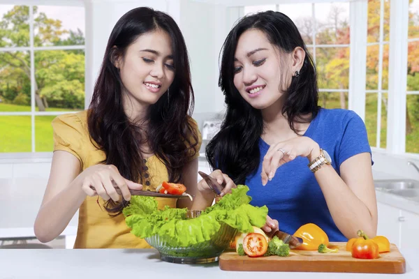 Duas meninas preparando salada — Fotografia de Stock