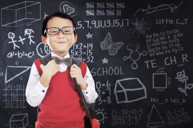 Üniformalı çocuk ve kara tahta üzerinde karalamalar
