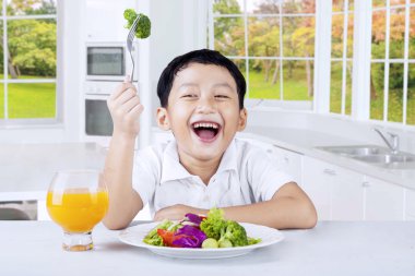 Sevimli çocuk mutfakta salata yiyor
