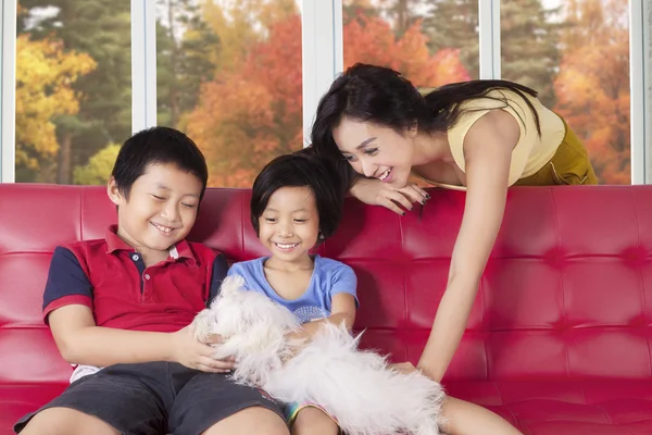 Kinderen en moeder spelen puppy thuis — Stockfoto