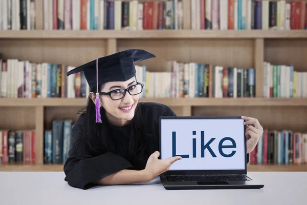 Abschlussschüler zeigt wie auf Laptop in Bibliothek — Stockfoto