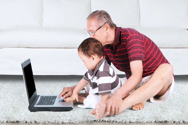 Avô e neto usando um laptop — Fotografia de Stock