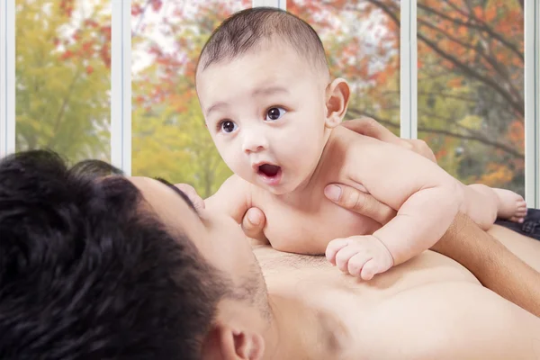 Bayi gembira di atas ayah dada di kamar tidur — Stok Foto