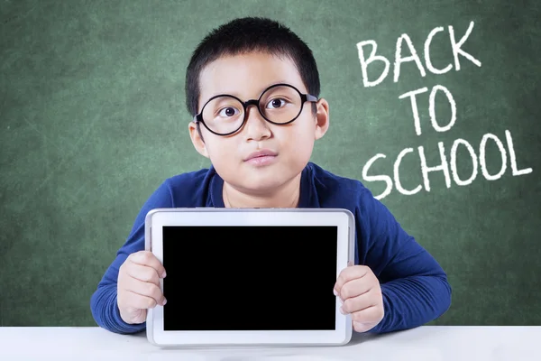 Pequeño colegial de vuelta a la escuela y sostiene la tableta — Foto de Stock