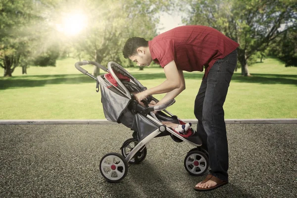 Mannen och hans baby med barnvagn på park — Stockfoto