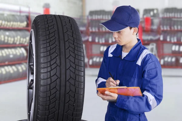 Mechanic checking tires in workshop — Stock Photo, Image
