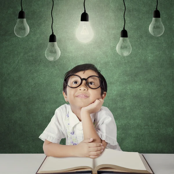 Primary school student sits under light bulb — Stock Photo, Image