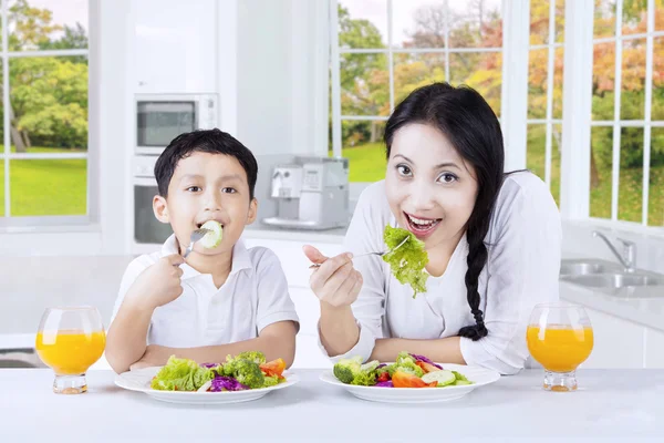 女人和她的儿子吃沙拉 免版税图库照片