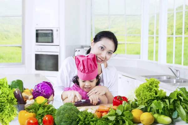 Sevimli kız ve annesi sebze yemek — Stok fotoğraf