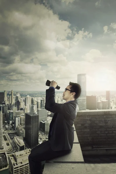 Бизнесмен смотрит на небо с биноклем — стоковое фото
