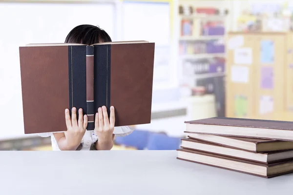 Маленькая студентка читает книги в классе — стоковое фото