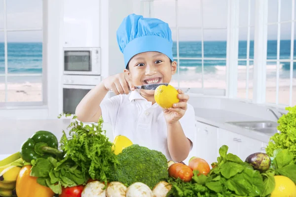 Petit garçon coupant un agrumes dans la cuisine — Photo