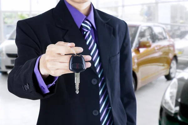 Hombre mostrando una llave de coche en la sala de exposición — Foto de Stock