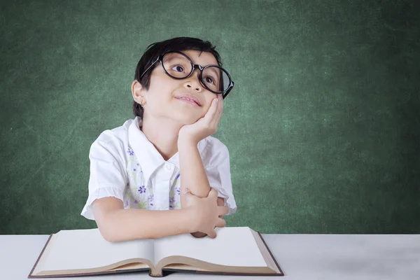 Studente della scuola primaria pensieroso si siede in classe — Foto Stock