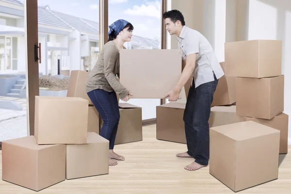 Young couple lift cardboard in new house — Stock Photo, Image