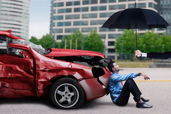 Homem com carro danificado senta-se sob guarda-chuva — Fotografia de Stock