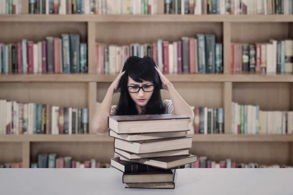 Aantrekkelijke vrouwelijke student stress kijken naar boeken in bibliotheek — Stockfoto