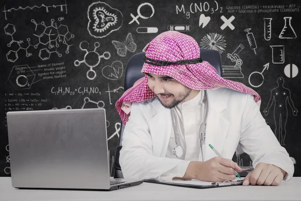 Арабский врач смотрит на ноутбук в лаборатории — стоковое фото