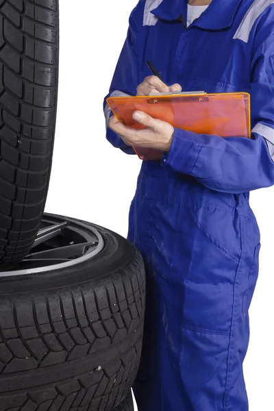 Mechaniker mit Klemmbrett inspiziert Reifen — Stockfoto