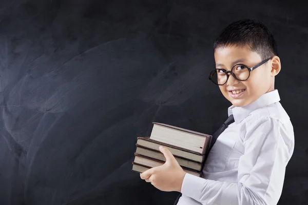 Menino detém livros e sorrindo na aula — Fotografia de Stock