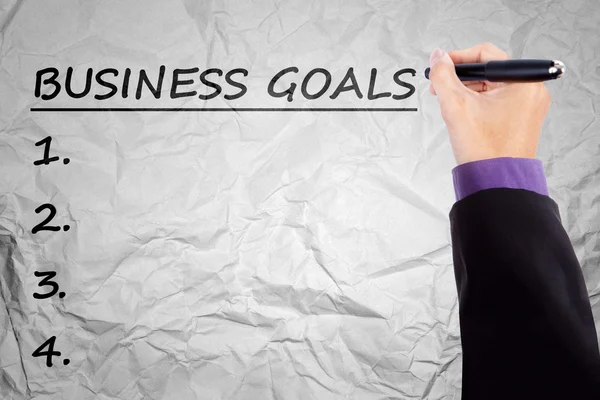 Hand writes business goals on crumpled paper — Stock Photo, Image