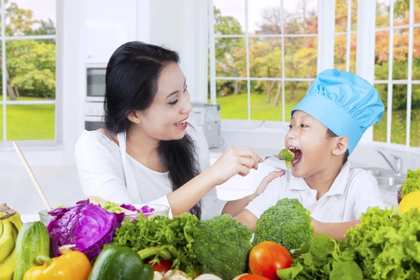 Mor ger grönsaker på hennes son — Stockfoto