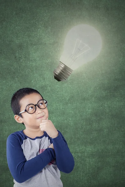 Boy wearing glasses and looking at bright lamp — Stock Photo, Image