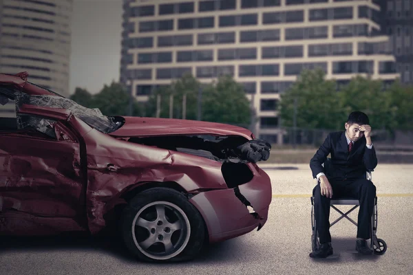 Personne handicapée avec fauteuil roulant et voiture endommagée — Photo