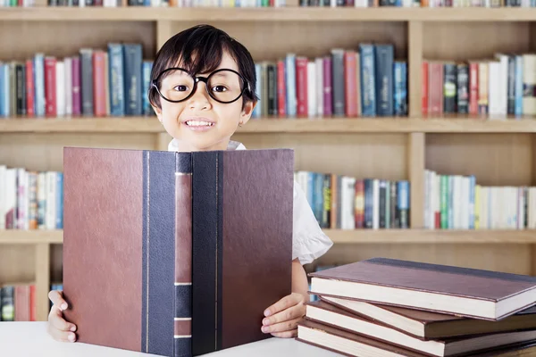 Nettes Schulmädchen liest Schulbücher in der Bibliothek — Stockfoto