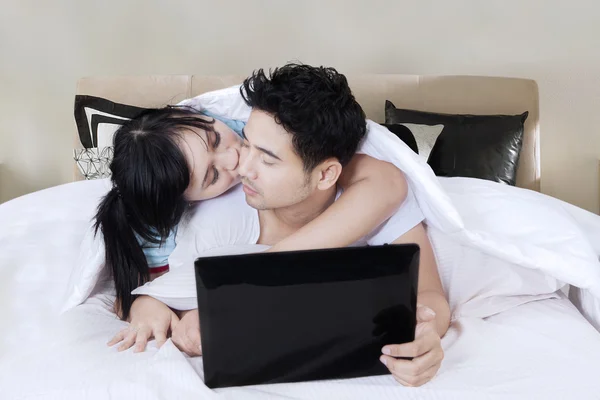 Casal beijando com laptop no quarto — Fotografia de Stock