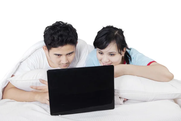 Couple relaxing on bed while using laptop — Stock Photo, Image