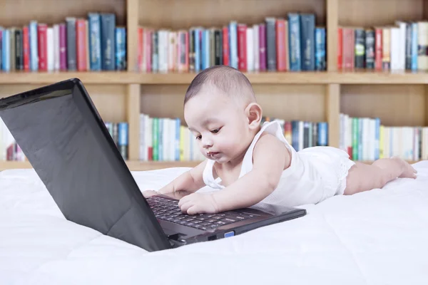 Criança engraçada com laptop e estante — Fotografia de Stock