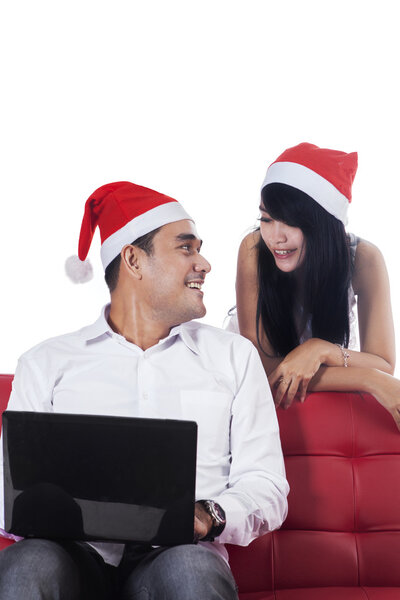 Young couple in santa hat using laptop